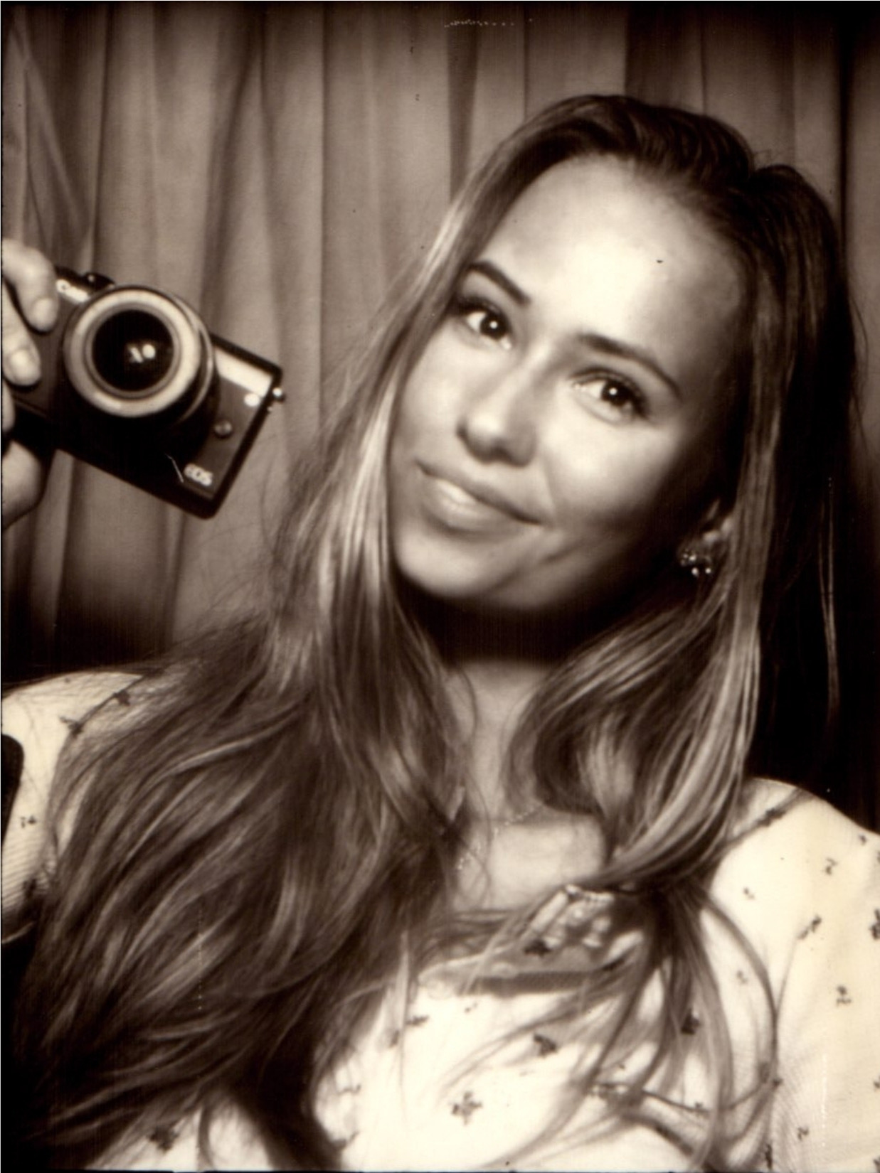 Zoe smiling with a camera in a vintage photo booth